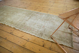 Angled view of vintage distressed Oushak runner's texture, revealing subtle beige and pink tones.