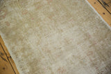 Distressed Oushak rug's worn texture, revealing subtle beige tones and faint pink details.