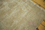 Distressed vintage Oushak rug close-up: worn sand-beige pile, visible foundation, pink hints.