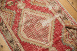 Detail of distressed Oushak rug with pale cherry red lattice motif and worn pile.