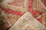 Vintage distressed Oushak rug detail, faded red patterns, worn pile, woven foundation.