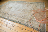 Distressed pile and decorative border of a vintage Oushak rug, showcasing faded ivory and green tones.