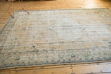 Distressed vintage Oushak rug with faded sea-foam green and charcoal floral border.