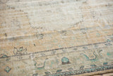 Distressed Oushak rug pile showcasing muted ivory, beige, and sea-foam floral patterns.