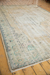 Distressed vintage Oushak rug corner showing faded floral patterns and sea-foam green accents.