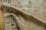 Visible wear and exposed foundation on a distressed vintage Oushak rug in neutral beige.