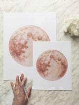 Two sizes of the Warm Moon watercolor art print by Katelyn Morse.