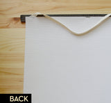 Back of moon phases pull down chart, showing canvas texture and cream hanging strap.
