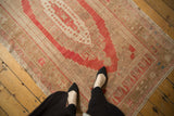 Faded raspberry red and bronze motifs on a vintage distressed Oushak rug's low pile.