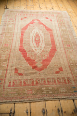 Distressed low pile and faded cochineal red medallion contour of a vintage Oushak rug.