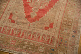 Distressed Oushak rug corner, showing faded bronze and pale raspberry red patterns.