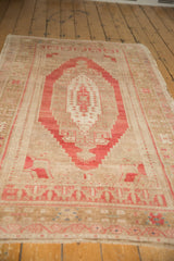 Faded pale red, bronze, and ivory geometric patterns on a distressed Oushak rug end.