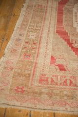 Distressed Oushak rug's low pile with faded bronze and pale raspberry patterns.