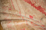 Distressed texture of a vintage Oushak rug with faded red and beige geometric patterns.