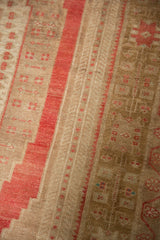Faded cochineal red stripe and bronze geometric motifs on distressed Oushak rug pile.