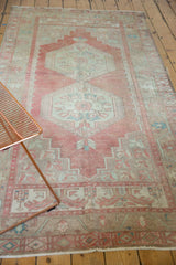 Distressed vintage Oushak rug detail showing muted blush, beige, and seafoam floral patterns.