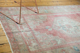Distressed texture and decorative blush, beige, seafoam geometric patterns on an Oushak rug.