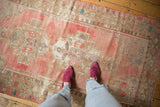 Distressed vintage Oushak rug runner with blush and beige geometric patterns, highlighting texture and wear.