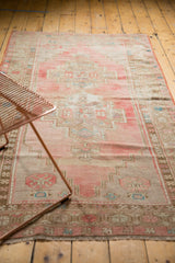 Faded pink and beige vintage Oushak rug runner showing textured wear and geometric patterns.
