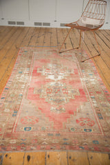 Distressed vintage Oushak runner with faded pink and aqua geometric border motifs.
