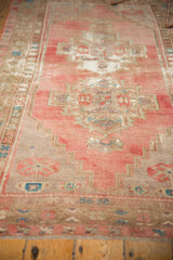 Distressed Oushak runner's geometric pattern in faded blush, aqua, and beige, with textured pile and wear.