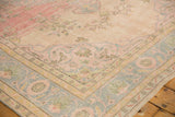 Distressed Oushak rug's worn pile, revealing pale pink and powder blue border motifs.
