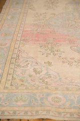 Distressed vintage Oushak rug texture, showing faded ivory, blush, and blue floral motifs.