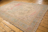 Distressed Oushak rug side edge showing faded pink and powder blue border motifs.
