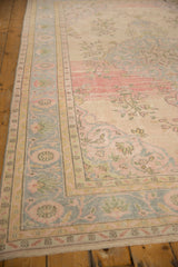 Distressed vintage Oushak carpet border, showing worn ivory, blush, and blue scrolling vinery.