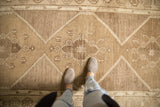 Time-softened silver and bronze tones on the stepped border of a distressed Oushak rug.
