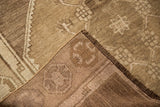Distressed Oushak rug's low pile texture, secured edge, and muted bronze silver tones.