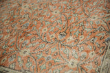 Distressed Oushak close-up: worn pile texture, pale rust orange, ivory, blue floral vinery.