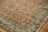 Distressed vintage Oushak corner displaying pale rust, ivory, chocolate floral vines, and meandering border.