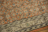 Distressed Oushak carpet detail: pale rust field, scrolling florals, and worn light border.