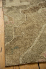 Secured edge of the vintage Oushak rug, featuring low pile and muted beige rectilinear patterns.