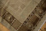 Distressed Oushak rug corner, showing dark bronze germinating seed border, and worn ivory field with light seafoam.