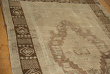 Distressed vintage Oushak rug showing faded bronze geometric patterns and worn pile texture.