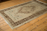 Distressed vintage Oushak rug with visible wear, muted bronze and ivory colors.