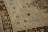 Dark chocolate bronze border with geometric motifs and distressed ivory pile texture.