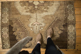 Vintage Oushak rug fragment with geometric medallion, scrolling vinery, coffee, dark brown, and ivory tones.