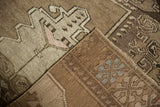 Vintage Oushak rug folded, revealing hand-knotted construction, geometric vinery motifs and blue-accented woven reverse.
