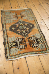 Distressed low pile Oushak rug corner with orange rust, mint, and oxidized geometric pattern.