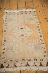 Distressed vintage Oushak rug showing peach and ivory pile, geometric border, and fringe.