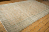 Distressed vintage Oushak carpet field showing faded pale orange and subtle vinery motifs.