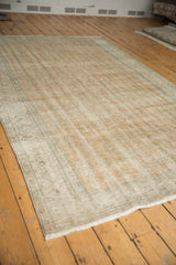 Worn pile and ivory fringe on a vintage distressed Oushak rug corner with faded hues.