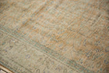 Distressed Oushak carpet close-up showing faded orange, seafoam green, and subtle floral vinery.