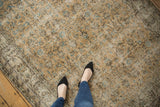 Distressed Oushak rug with faded beige, aqua, brown floral patterns, and visible wear.