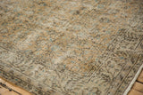 Detail of distressed Oushak rug with muted beige, aqua floral patterns and mostly even wear.