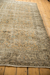 Distressed Oushak rug showcasing worn beige field with aqua vinery and winding border.
