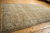 Distressed vintage Oushak rug corner showing floral vinery, aqua blue, and worn foundation.